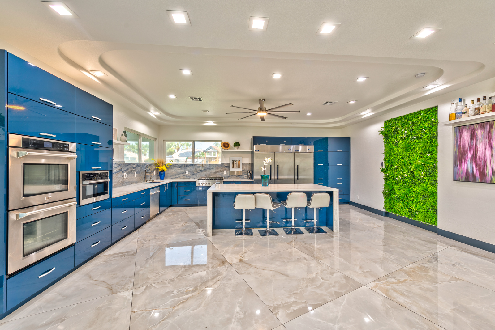 Modern kitchen remodel in Henderson with glossy blue cabinets, marble flooring, and built-in stainless appliances
