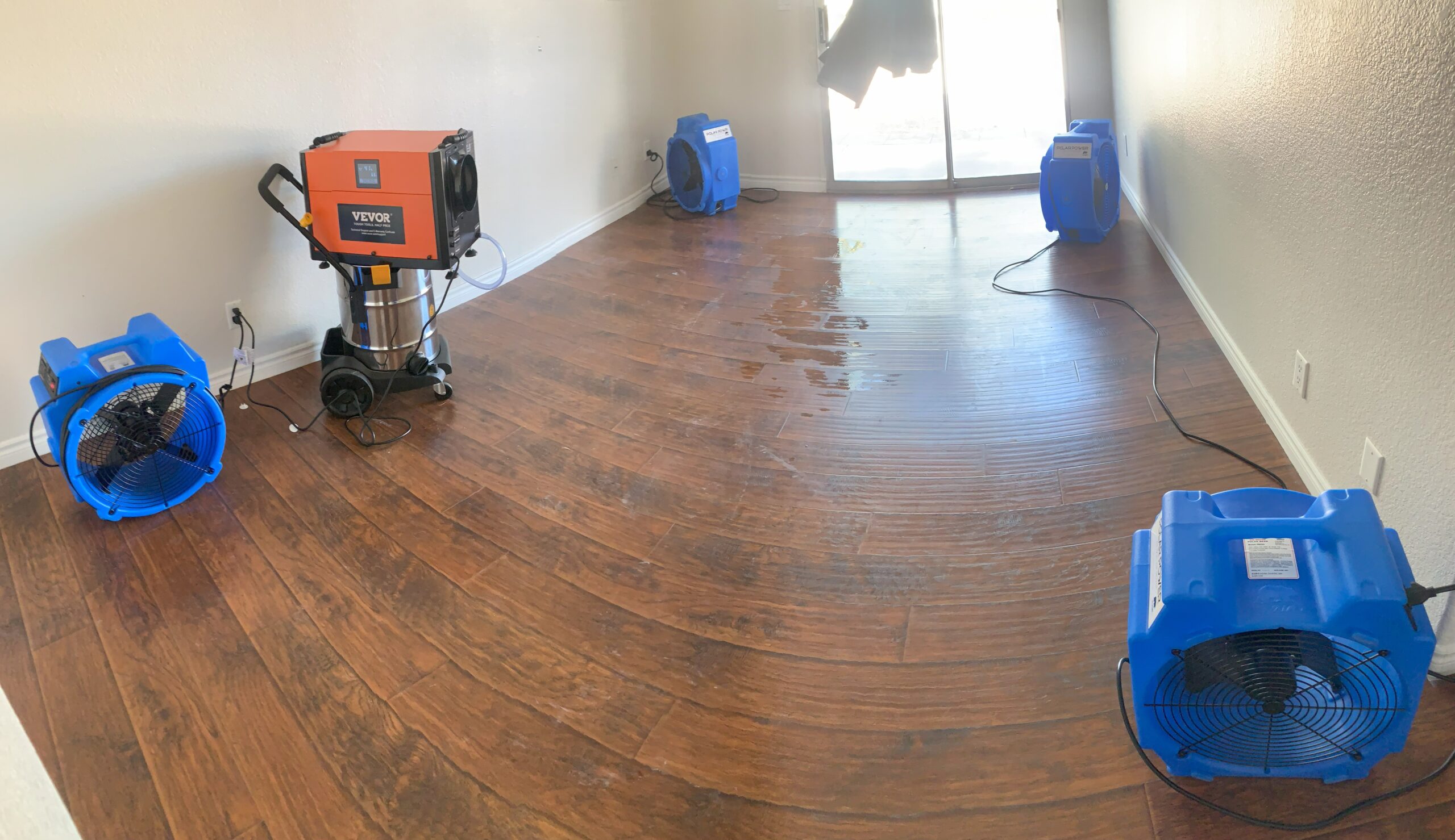 Industrial air movers and a dehumidifier drying water-damaged hardwood floors during a water damage restoration project in Summerlin