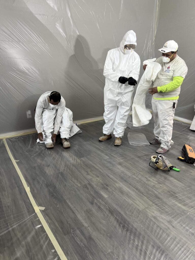 Technicians suiting up in PPE to sanitize and clean a water-damaged room