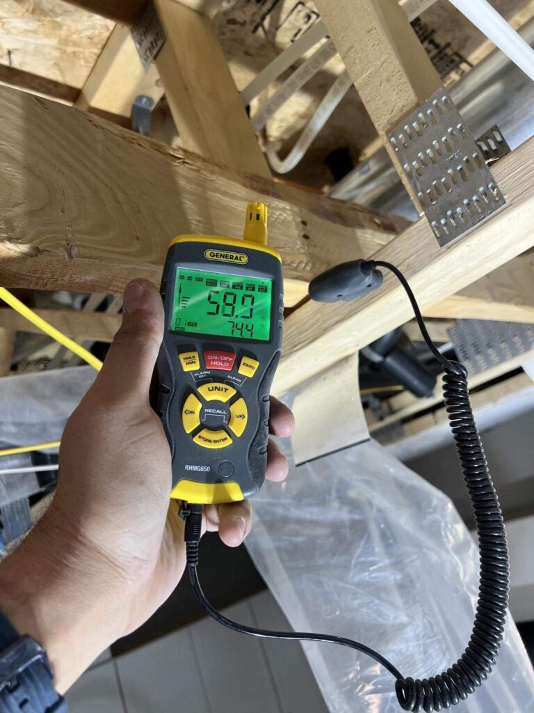 Moisture meter used during water damage inspection in attic framing
