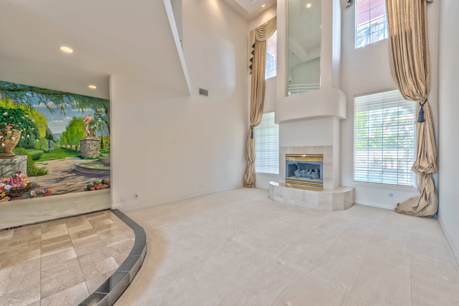Outdated foyer with carpet and gold-accent fireplace before renovation in Las Vegas