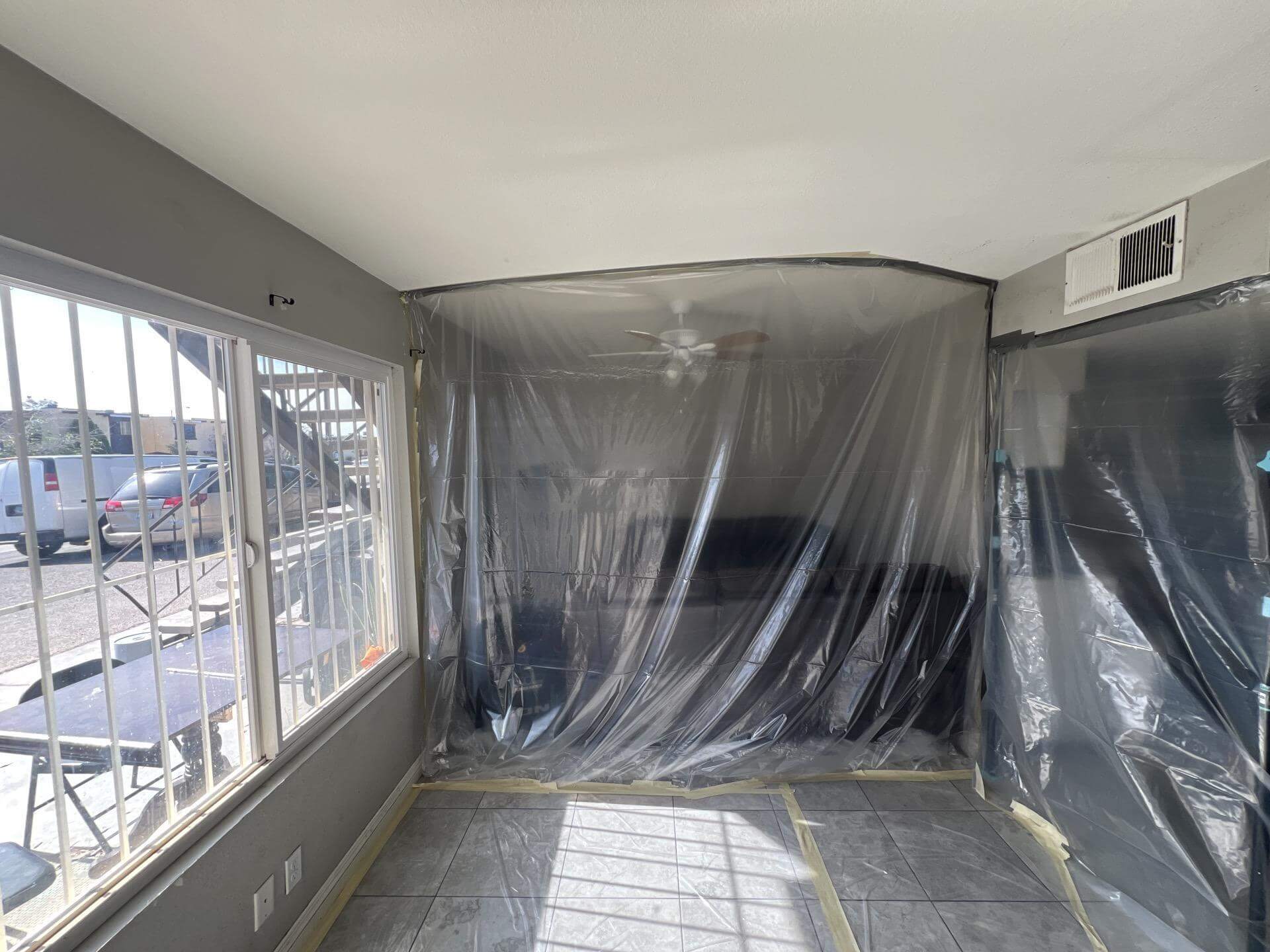 Plastic containment with floor protection set up in a Las Vegas living room to control water damage and dust during mitigation.