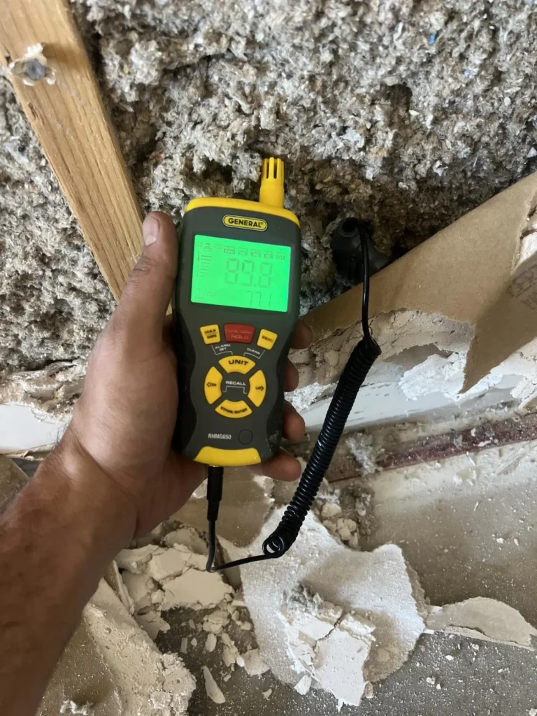Technician taking a moisture reading at an opened water-damaged wall in Summerlin