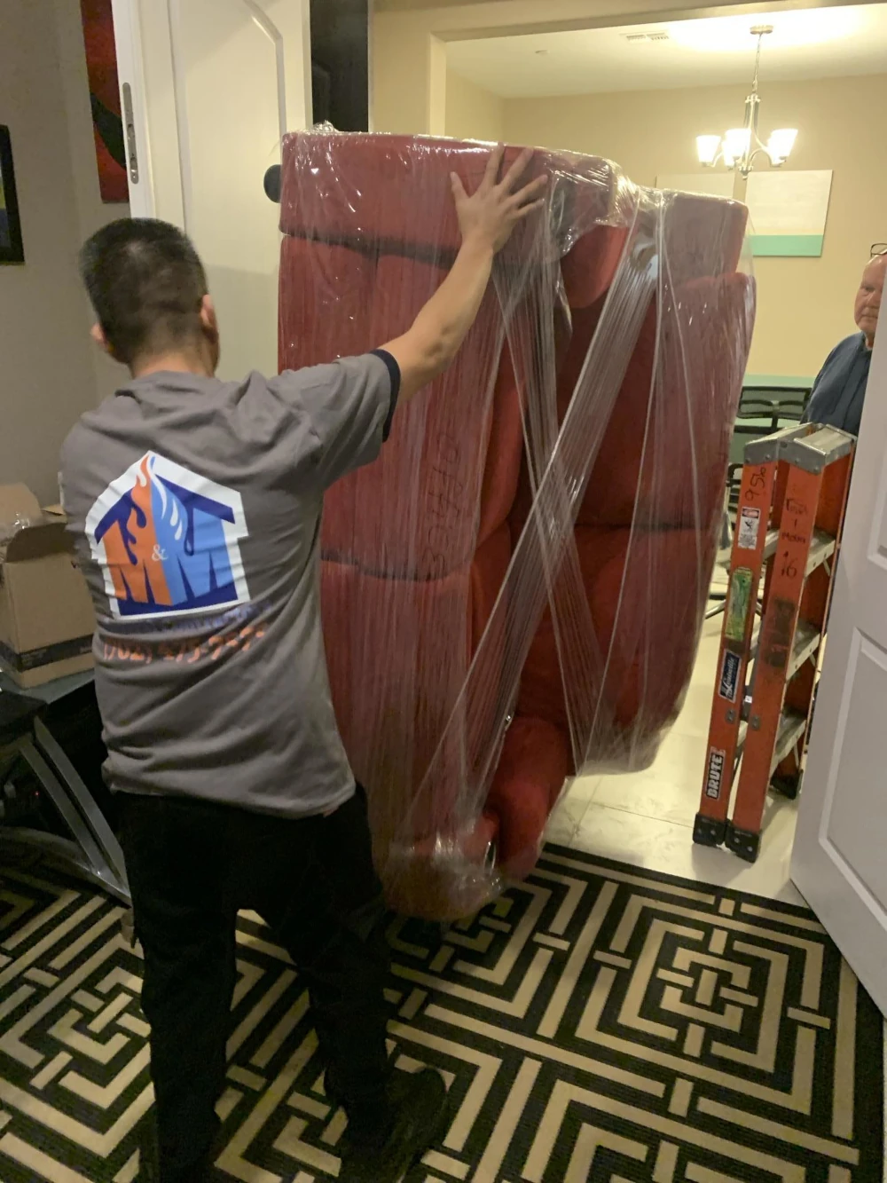 M&M Restoration technician shrink-wrapping and moving furniture during a contents pack-out in North Las Vegas