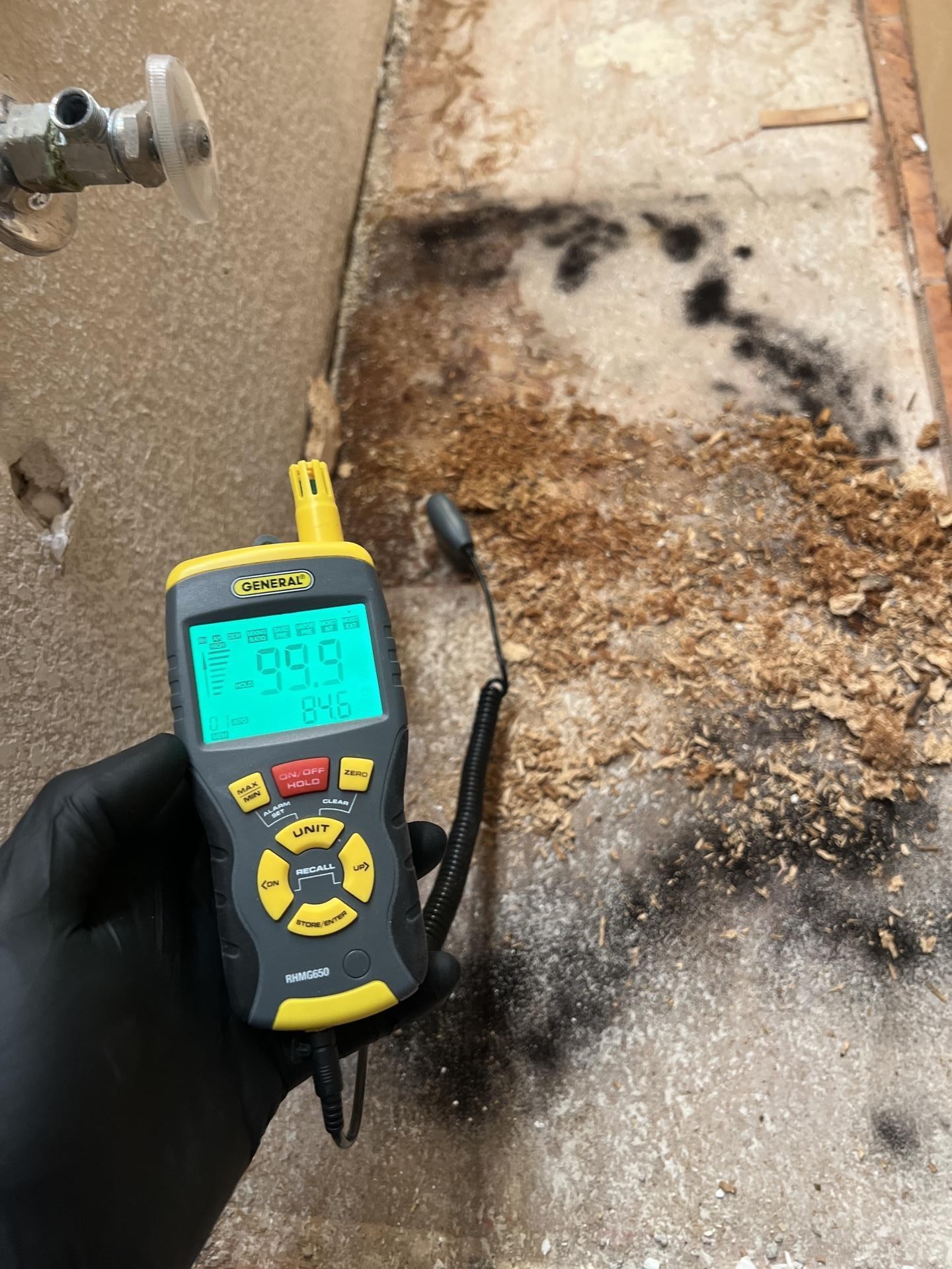 M&M Restoration technician taking moisture readings over a mold-stained subfloor after an AC water leak in Las Vegas